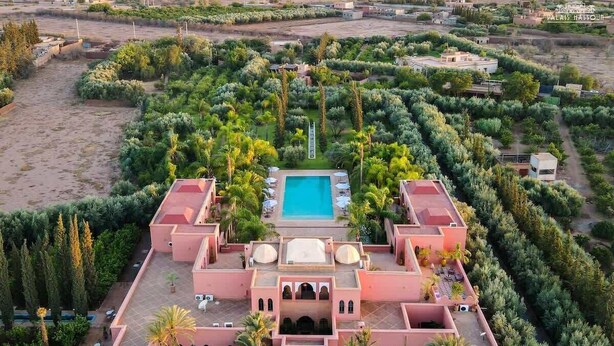 A large, pink-roofed building with a central pool, surrounded by lush greenery and palm trees. - Luxury villa, pool, spa and 5-star sercice (Makinat Sridi)