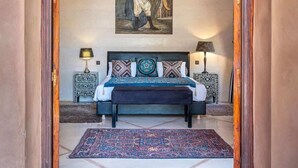 A bedroom with a large bed, a chandelier, a painting, and a rug. - Luxury villa, pool, spa and 5-star sercice (Makinat Sridi)