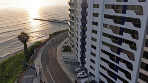 A high-rise building with a unique facade featuring circular cutouts and a view of the ocean.
