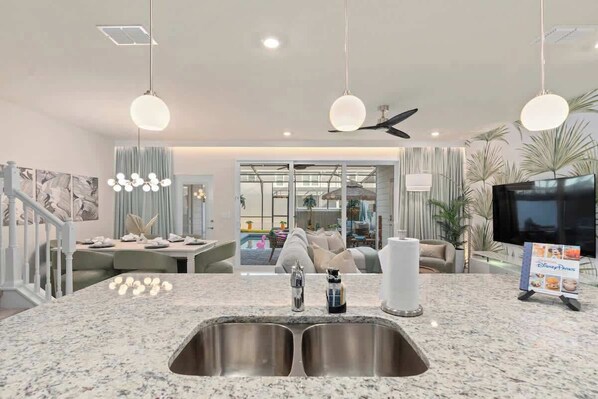 A modern kitchen with granite countertops, stainless steel sinks, and pendant lighting.