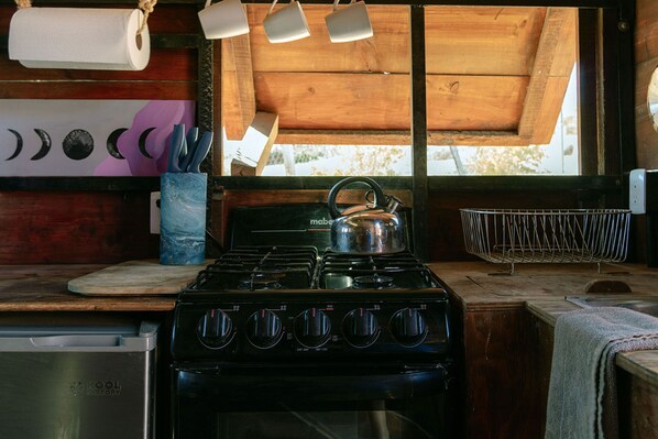 Una cocina con estufa, ollas y utensilios.