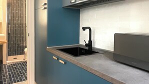 Een moderne keuken met blauwe kastjes, een zwarte spoelbak en een roestvrijstalen afzuigkap.