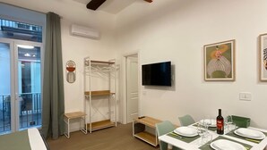 Een moderne kamer met een eettafel gedekt voor twee personen, een aan de muur bevestigde televisie en een balkon met een schuifdeur.