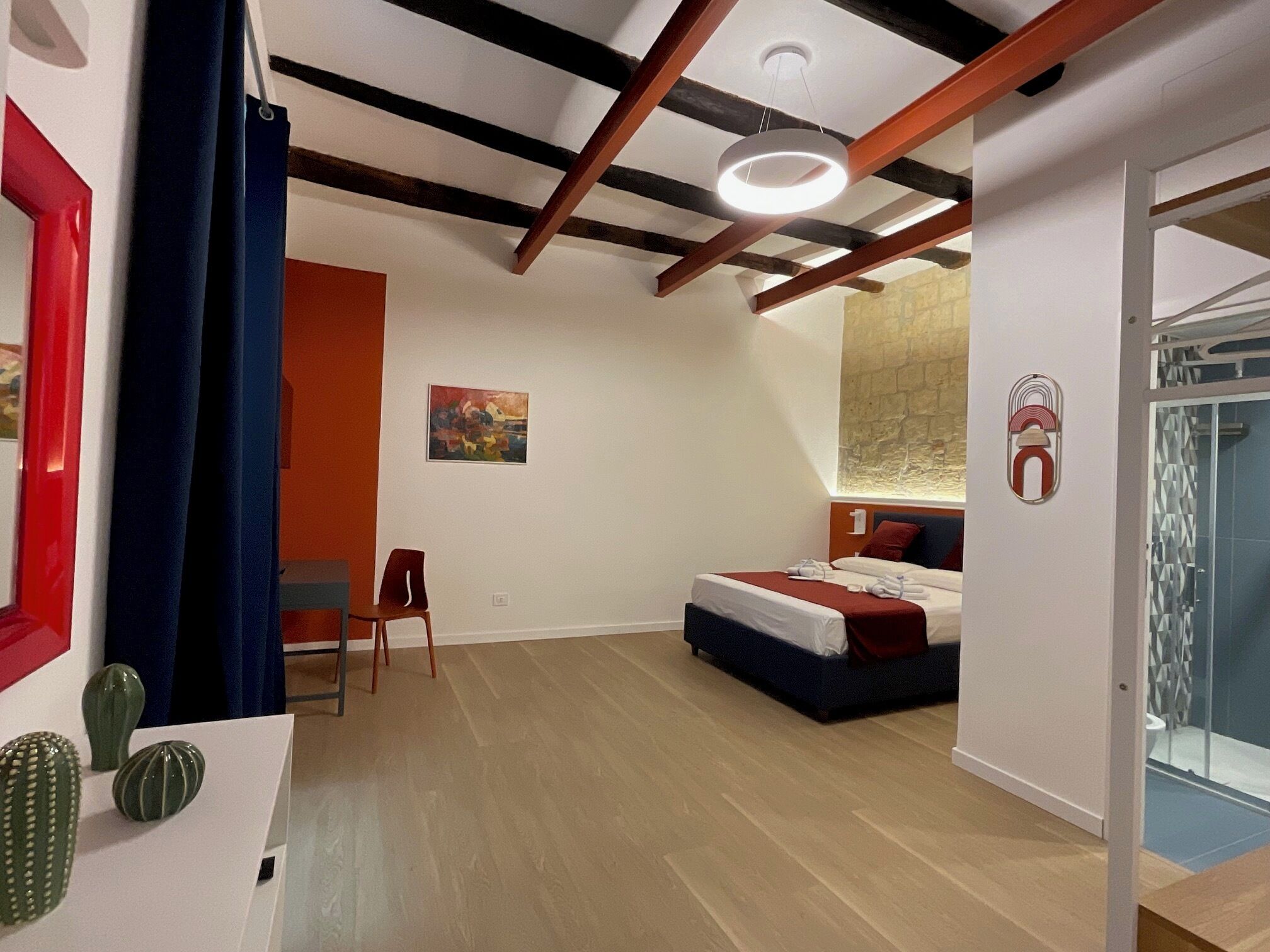 Una habitación de hotel moderna con cama, escritorio, silla y zona de ducha.