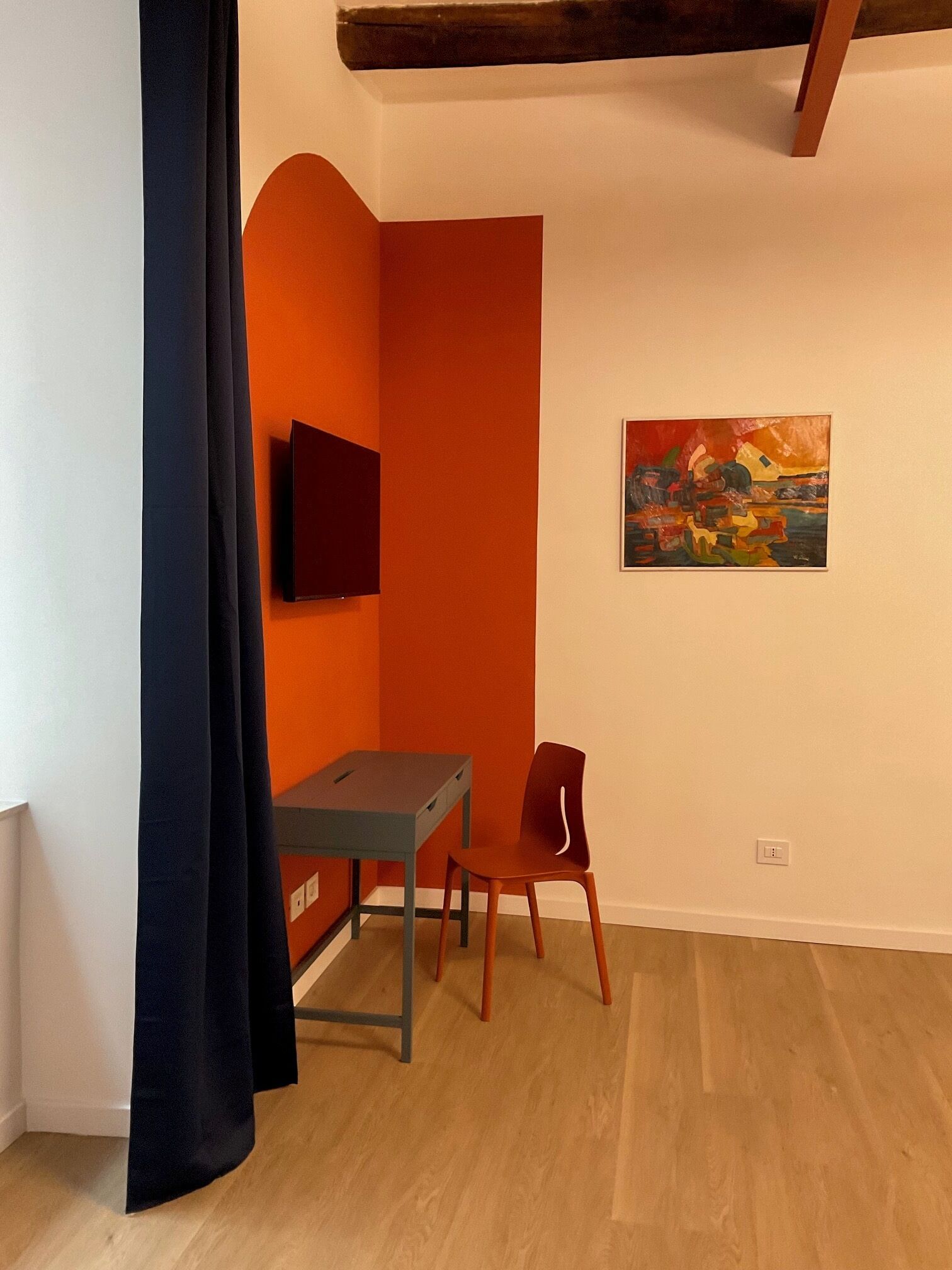 Una habitación con escritorio, silla y un cuadro en la pared.