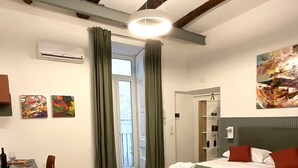 Een hotelkamer met een bed, een eettafel met borden en bestek, een groene stoel en een schilderij aan de muur.