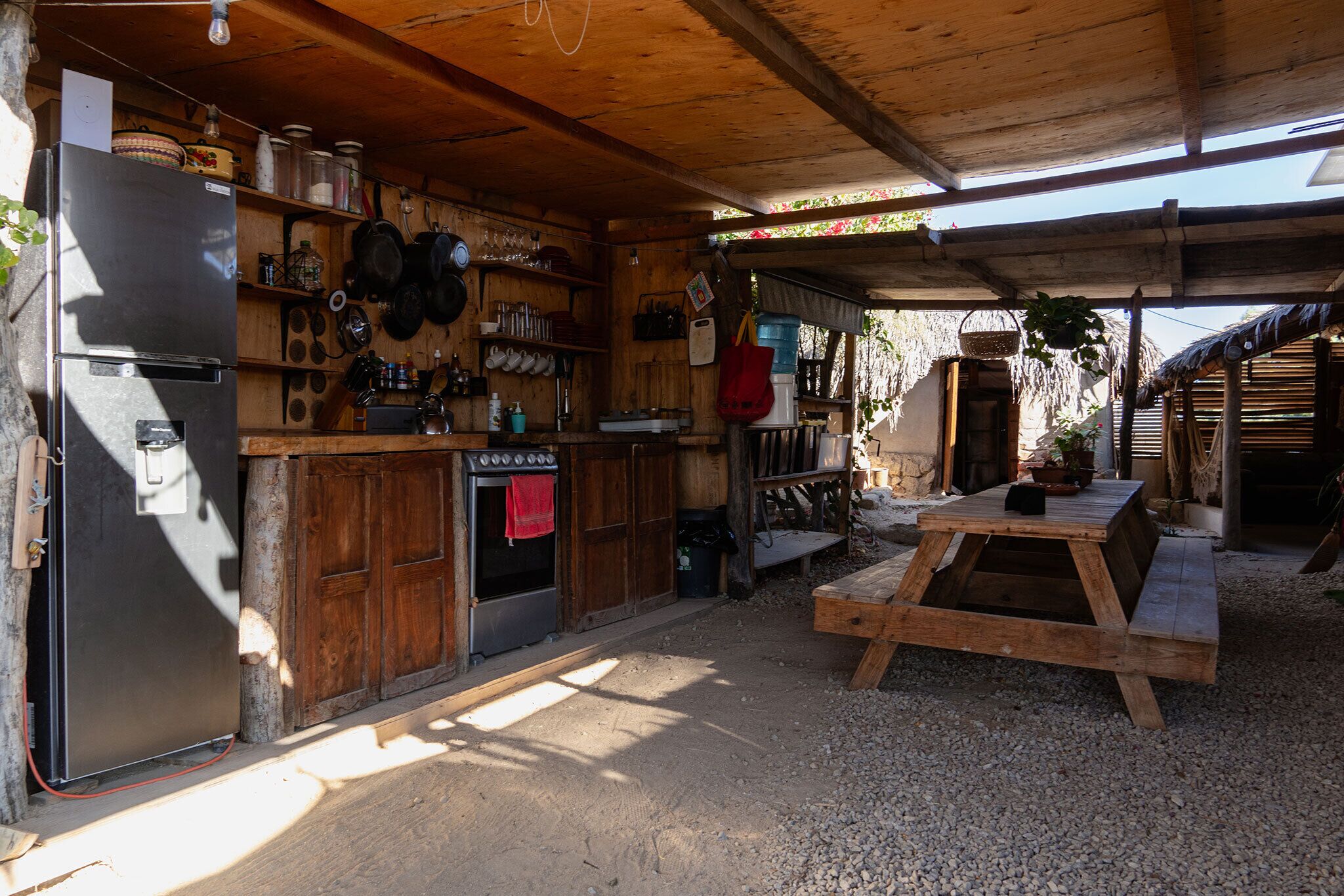 A rustic kitchen with a refrigerator, oven, and wooden shelves.