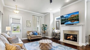 A living room with a fireplace, a large flat-screen TV, and a comfortable seating area. - Southern Comfort! Charming 3 Bedroom Between Baton Rouge and New Orleans (Geismar)
