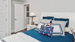 A neatly arranged bedroom with a bed, bedside table, lamp, and a door.