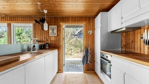 A modern kitchen with wooden walls, white cabinets, a built-in oven, and a large window. - Gorgeous home in Vejby with WiFi (Vejby)