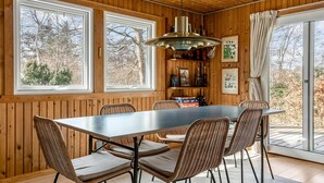 A dining area with a wooden interior, large windows, wicker chairs, and a table. - Gorgeous home in Vejby with WiFi (Vejby)