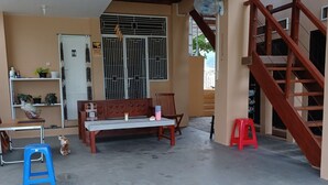 Un espace extérieur abrité comprenant un banc en bois, une table et un escalier.