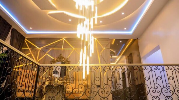 Ein modernes Interieur mit einer geometrischen Leuchte und einer Treppe mit aufwendiger Geländerarbeit.