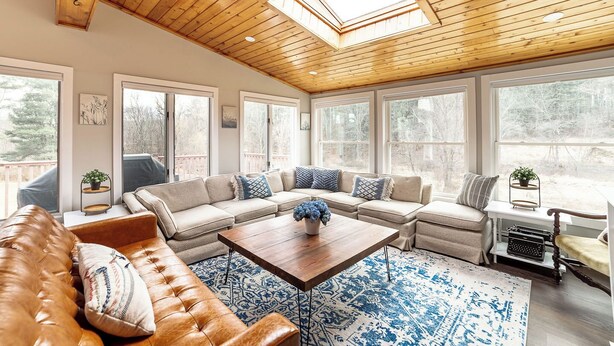 A cozy living room with a sectional sofa, a wooden coffee table, and a skylight.