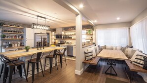 A modern kitchen with a central island, bar stools, and a dining area with benches.