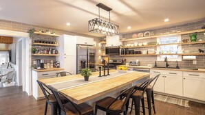 A modern kitchen with a central island, built-in appliances, and open shelving.