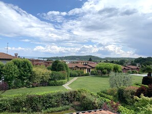 A residential area with houses, a lawn, and a distant body of water. - Garda Pleasure By Bookinggardalake (Padenghe sul Garda)