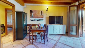 Un coin repas avec une table et des chaises en bois, un téléviseur et un meuble.