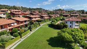 A residential area with terraced houses, a central lawn, and a small white building. - Garda Pleasure By Bookinggardalake (Padenghe sul Garda)