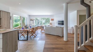 A spacious modern kitchen with a central island, wooden dining area, and a staircase leading to an upper level. - CHARMING VILLA WITH HEATED POOL OVERLOOKING THE GOLF COURSE (SEIGNOSSE)