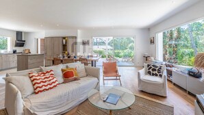 A spacious living area with a sofa, coffee table, and a dining area with chairs. - CHARMING VILLA WITH HEATED POOL OVERLOOKING THE GOLF COURSE (SEIGNOSSE)