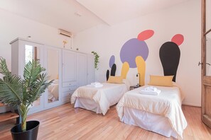 Un dormitorio moderno con dos camas, un espejo grande y una planta en maceta.