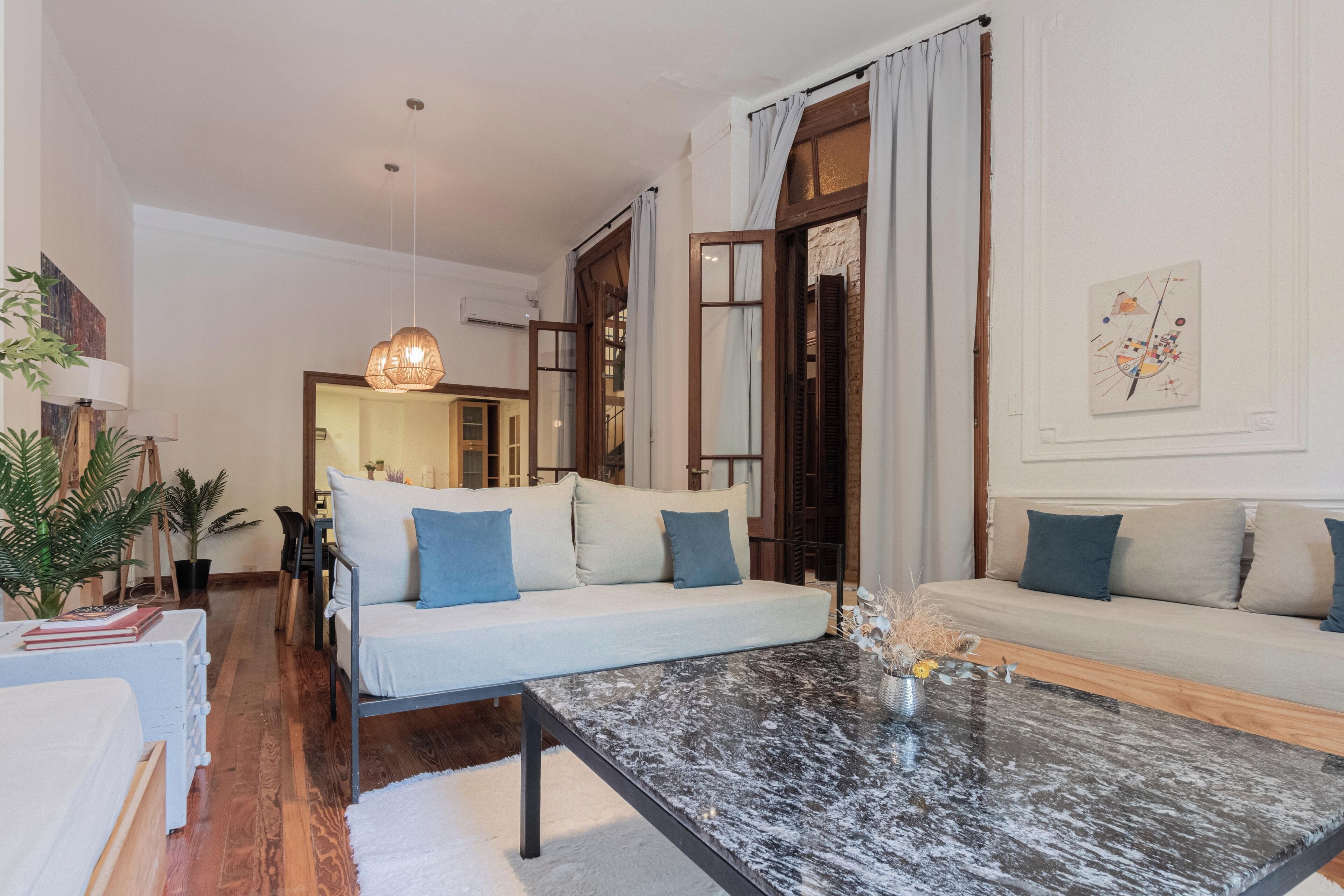 A modern living room with a sofa, a coffee table, and a dining area with chairs.