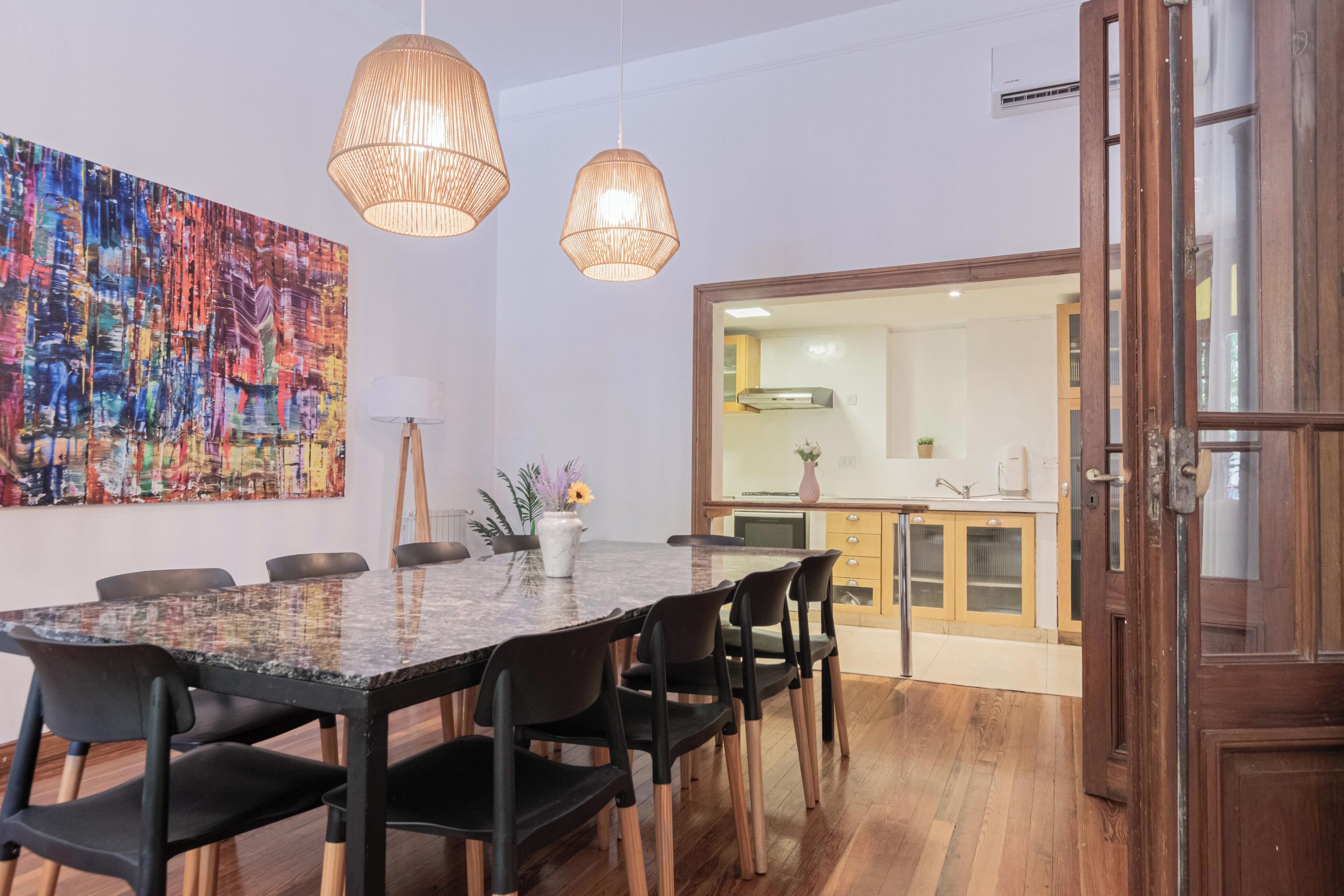 Uma sala de jantar com uma mesa grande, cadeiras e luminárias pendentes.