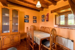 Un comedor con una mesa, sillas, un armario con puertas de vidrio y un radiador.