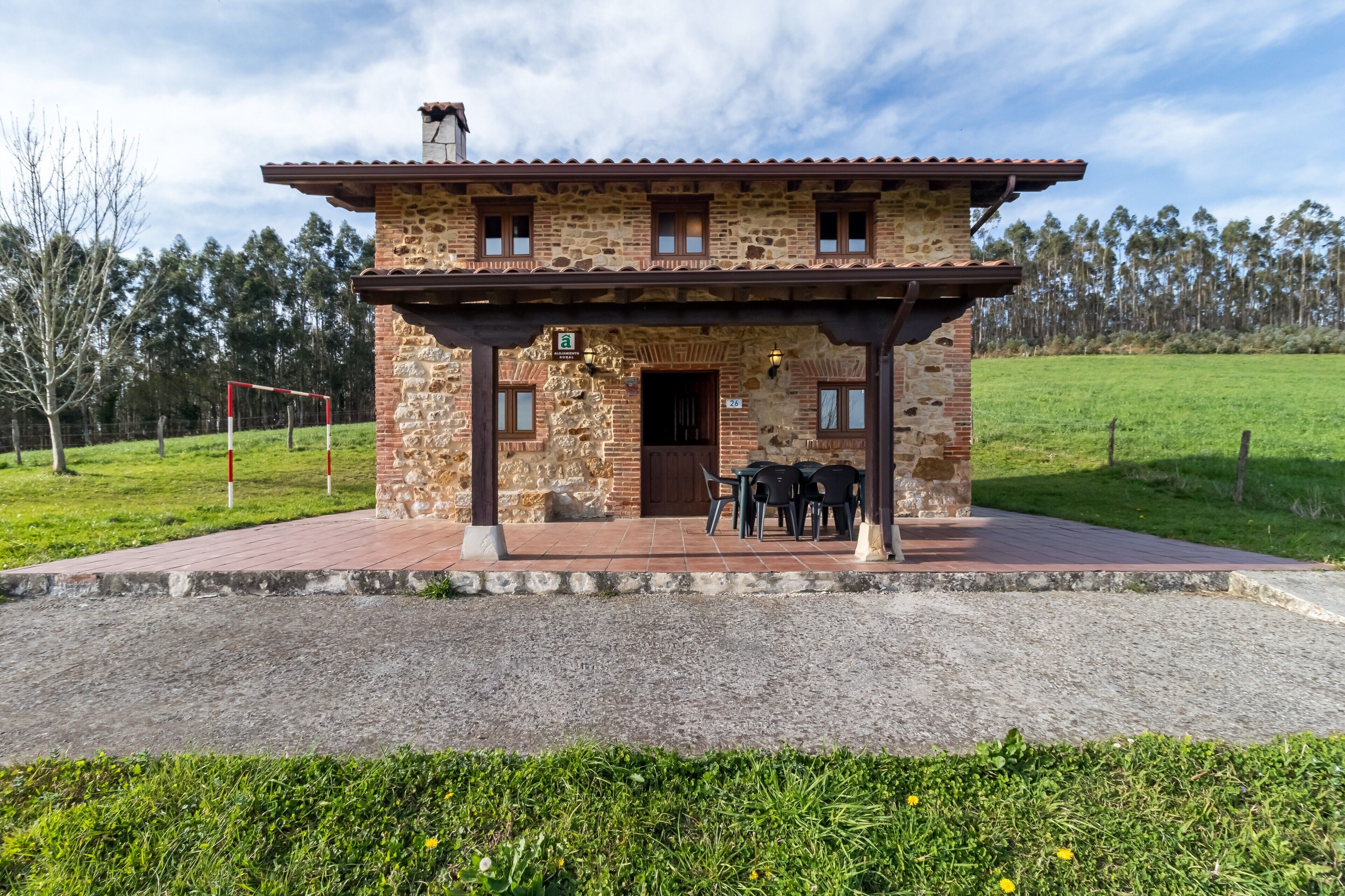 A stone building with a covered patio, a door, and a sign indicating a room number.
