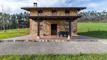 A stone building with a covered patio, a door, and a sign indicating a room number.