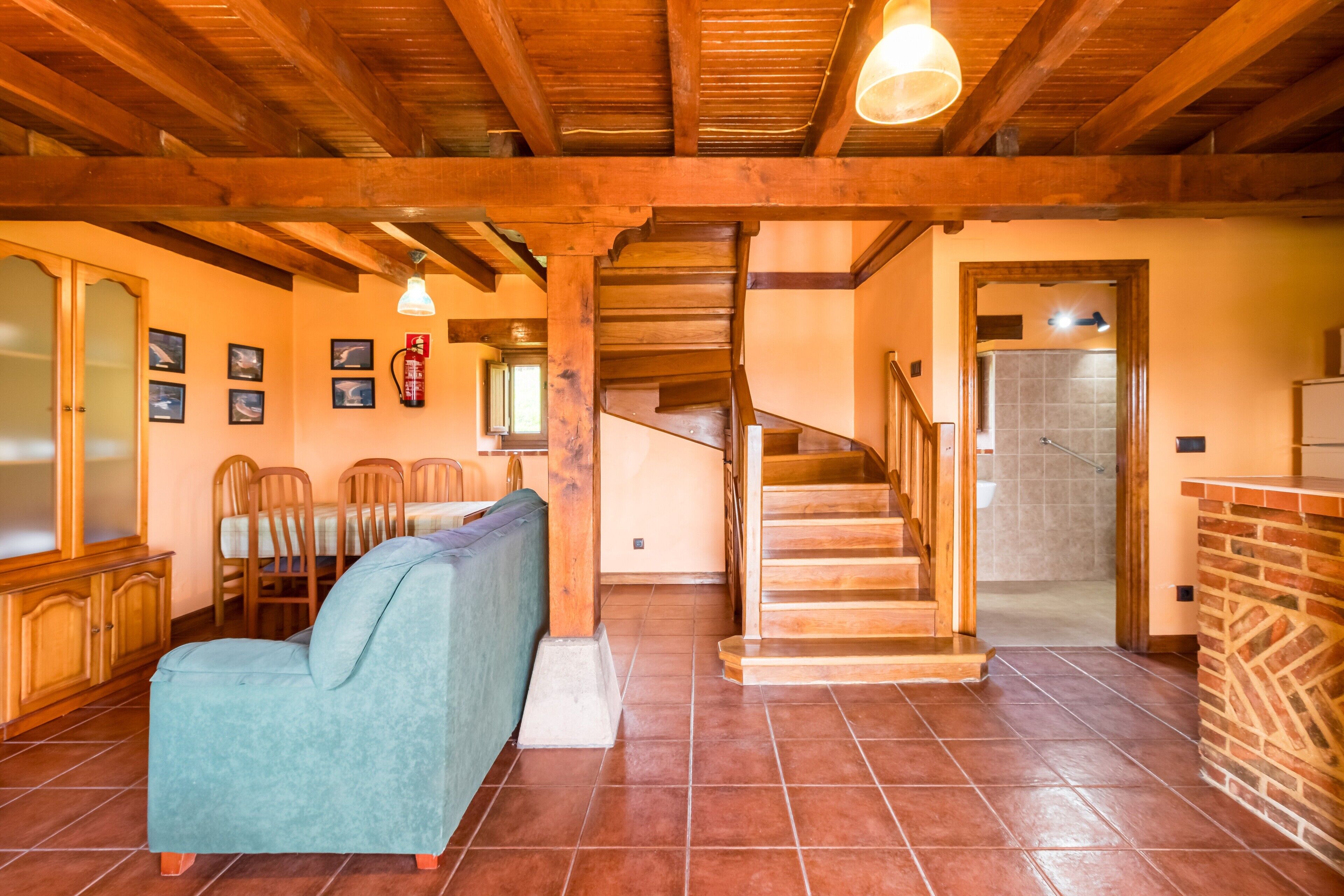 Amplia sala de estar con una escalera de madera, una mesa de comedor con sillas y un sofá.