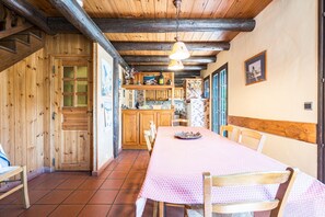 A wooden interior with a dining table, chairs, a kitchen area, and a staircase.