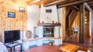 A wooden interior with a fireplace, a television, and a staircase. - Chalet 'Le Tougne' with Mountain View, Private Terrace and Balcony (Champagny-en-Vanoise)