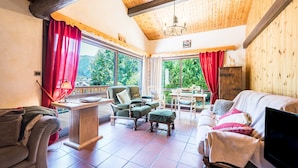 A cozy living room with a wooden ceiling, a sofa, a chair, a table, and a television. - Chalet 'Le Tougne' with Mountain View, Private Terrace and Balcony (Champagny-en-Vanoise)