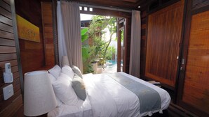 A bedroom with a bed, a lamp, a painting, and a view of a pool and greenery. - Moin Villa Lembongan (Bali)