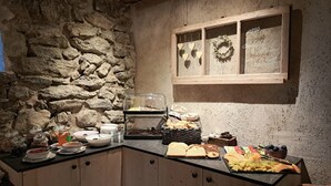 A buffet setup with various food items, a stone wall, and a wooden-framed window with a wreath.