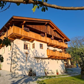 A multi-story wooden chalet with balconies, a cross, and outdoor seating. - Apartment 'Lauterfresser' with Mountain View, Shared Garden and Wi-Fi (Rodeneck)