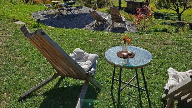 Een gazon met een tafel, stoelen en een parasol.