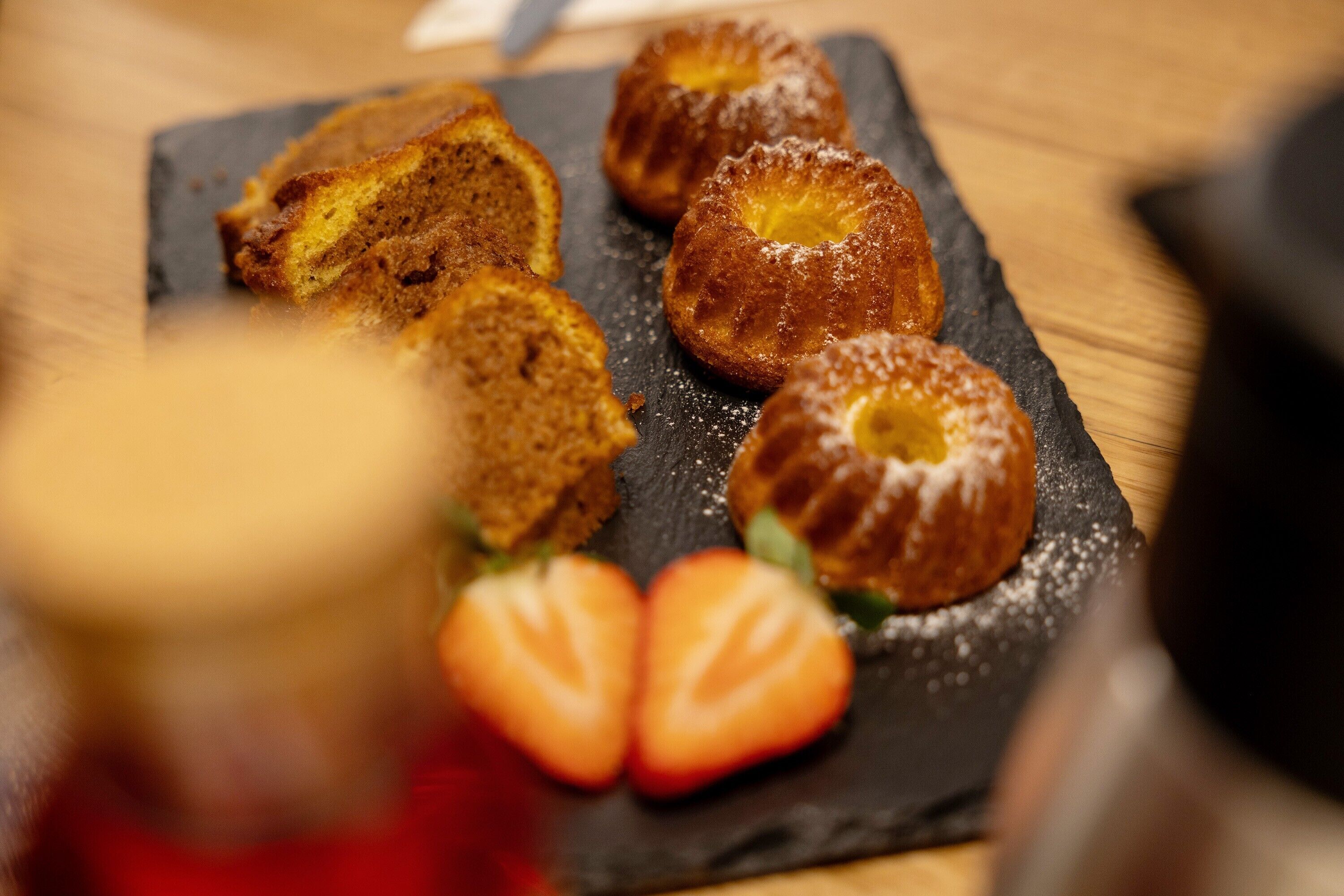 Un plat de postres amb pastissos i maduixes sobre una taula de pissarra.