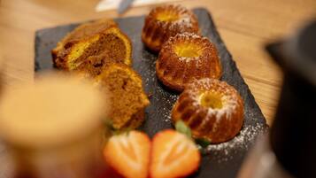 Un plat de postres amb pastissos i maduixes sobre una taula de pissarra.