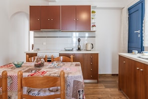 A compact kitchen with wooden cabinets, a white countertop, and a dining table with a patterned tablecloth.