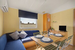 Un espacio habitable compacto con sofá, mesa de comedor y televisor.