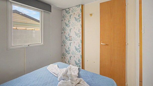 Una camera da letto con un letto singolo, una finestra, una porta e vista su un edificio.
