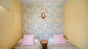 A room with two beds, a floral wallpaper, and a hanging decoration. - Holiday Home 'El Olivo 2' with Shared Pool, Wi-Fi & Air Conditioning (Chiclana de la Frontera)