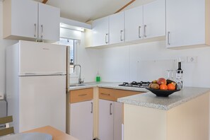 A modern kitchen with white cabinets, a built-in refrigerator, a gas stove, and a fruit bowl on the countertop.