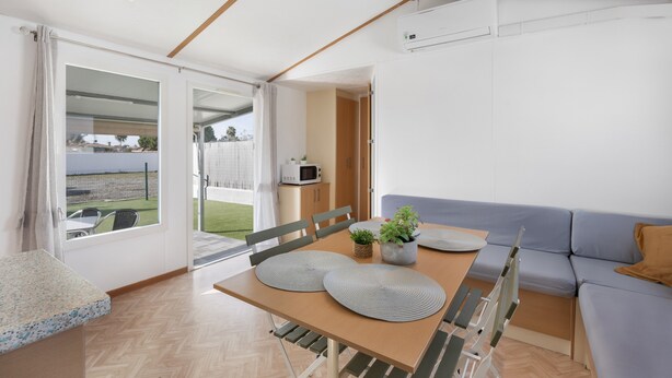 Un interior moderno con una mesa de comedor, sillas, un sofá y vistas a través de un ventanal.