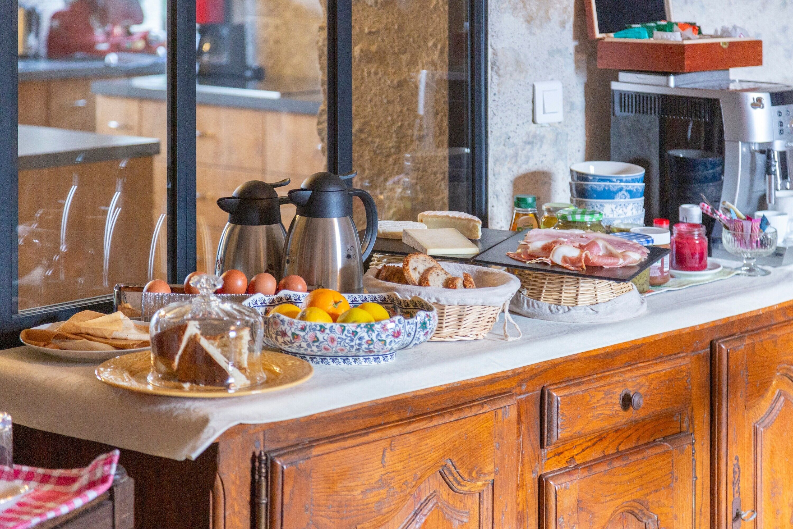 Een ontbijtbuffet met diverse gerechten, een koffiezetapparaat en een schaal fruit.