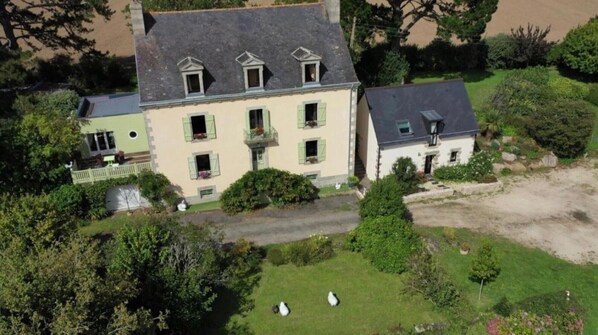 Une vue aérienne d’une maison à deux étages, dotée d’un toit en pente, de nombreuses fenêtres et d’une pelouse bien entretenue.