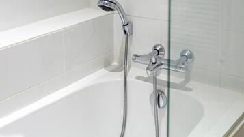 Une salle de bain moderne avec une douche à parois de verre, des robinetteries chromées et des murs recouverts de carreaux blancs.